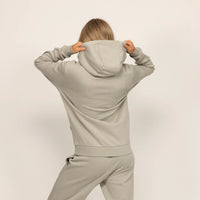 Woman wearing Marame cotton fleece hoodie in Wolf Grey, rear view.