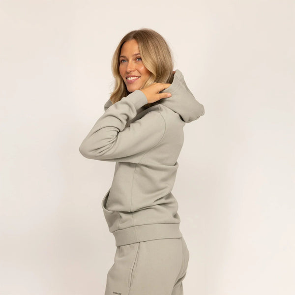 Woman wearing Marame cotton fleece hoodie in Wolf Grey, side view.|wolf green