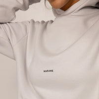 Woman wearing a cotton fleece Logo Hoodie in Ash White, closeup.
