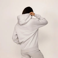 Woman wearing a cotton fleece Logo Hoodie in Ash White, rear view.|ash white