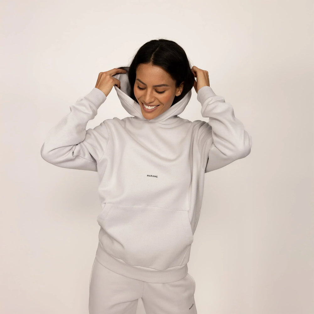 Woman wearing a Marame cotton fleece Logo Hoodie in Ash White, front view.