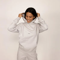 Woman wearing a Marame cotton fleece Logo Hoodie in Ash White, front view.
