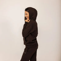 Woman wearing cotton fleece Logo Hoodie in Smoked Brown, side view.