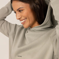 Woman wearing a cotton fleece Logo Hoodie in Wolf Grey, closeup.|wolf green