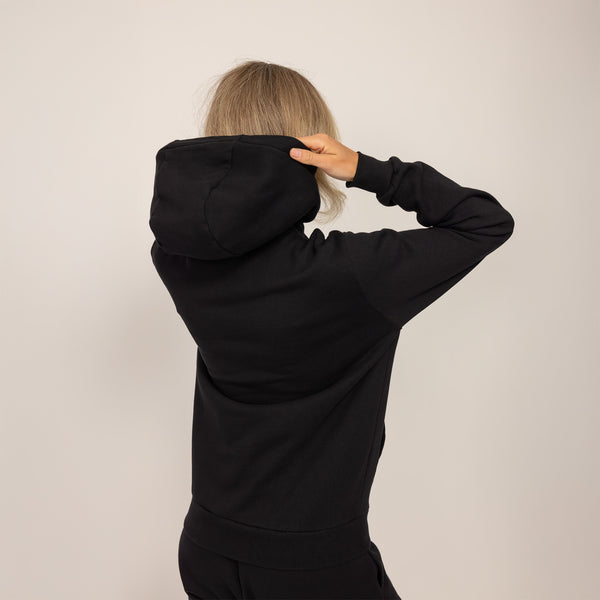 Woman wearing cotton fleece hoodie in Black, rear view.