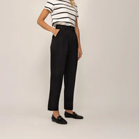 Woman wearing Marame High-Waisted Tapered Trousers in Black, front view.