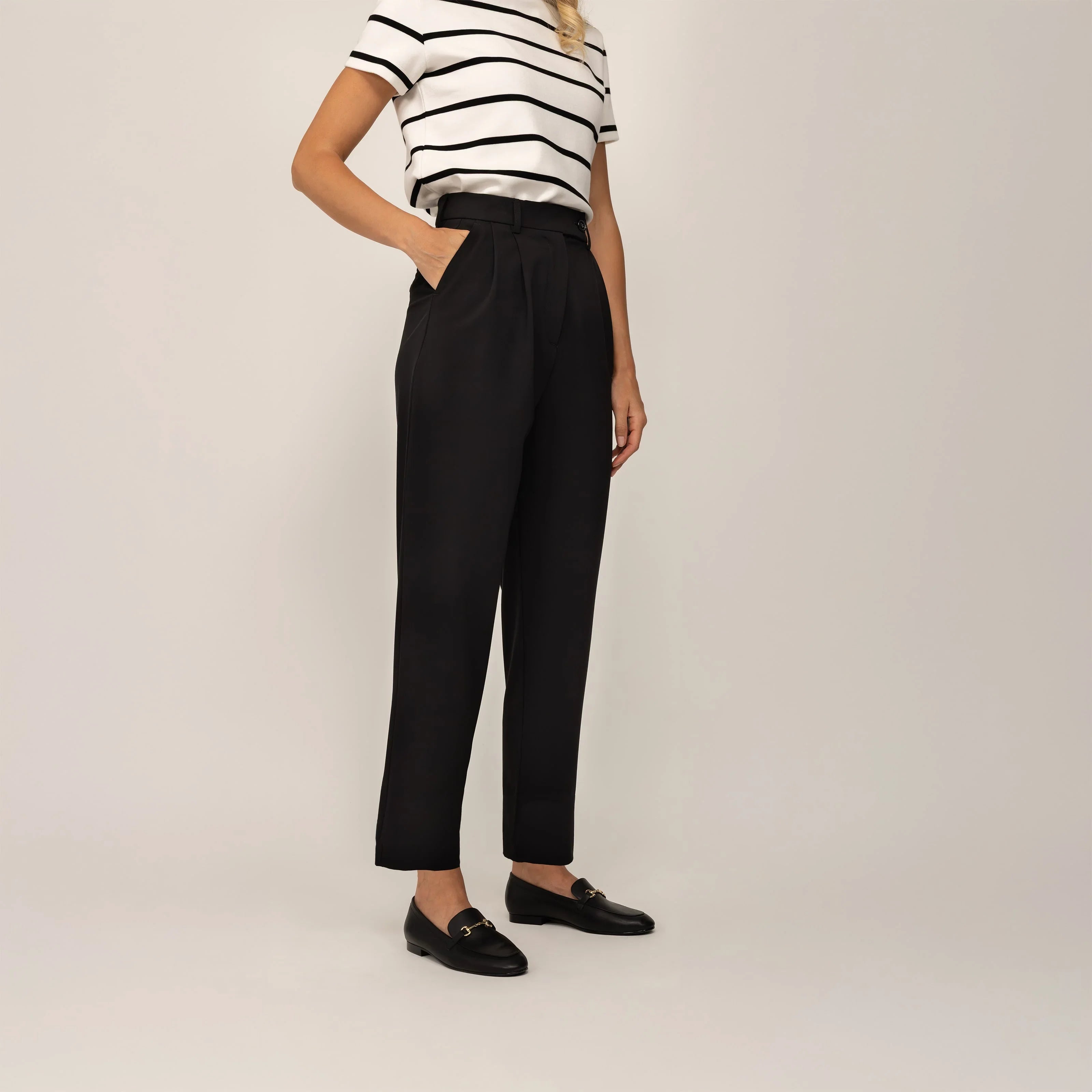 Woman wearing Marame High-Waisted Tapered Trousers in Black, front view. |black