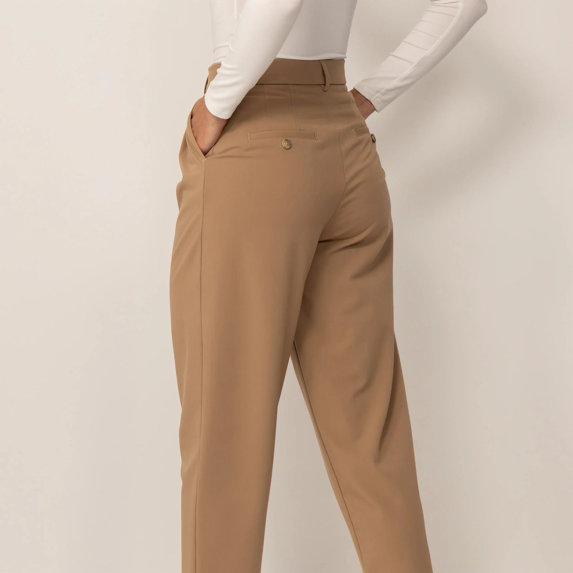 Woman wearing High-Waisted Tapered Trousers in Caramel, rear view. |caramel