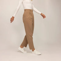 Woman wearing Marame High-Waisted Tapered Trousers in Caramel, front view. |caramel