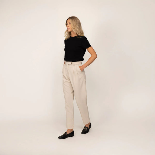 Woman wearing Marame High-Waisted Tapered Trousers in Stone, full view.