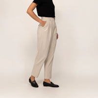 Woman wearing Marame High-Waisted Tapered Trousers in Stone, front view.