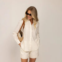 Woman wearing off white linen blend shirt and shorts with sunglasses